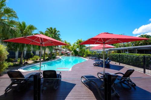 a pool with chairs and umbrellas next to a resort at Mango Lagoon Resort & Wellness Spa in Palm Cove