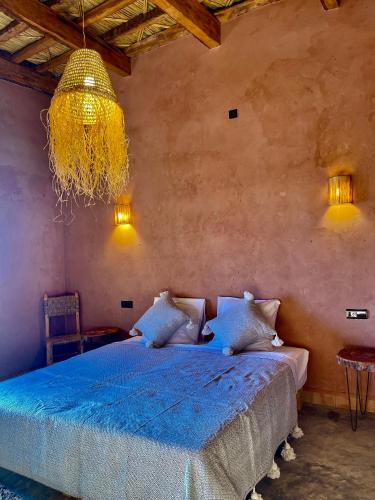 ein Schlafzimmer mit einem blauen Bett und einem Kronleuchter in der Unterkunft Dar Zitoune - Authentic Stay in Tagounite in Tagounite