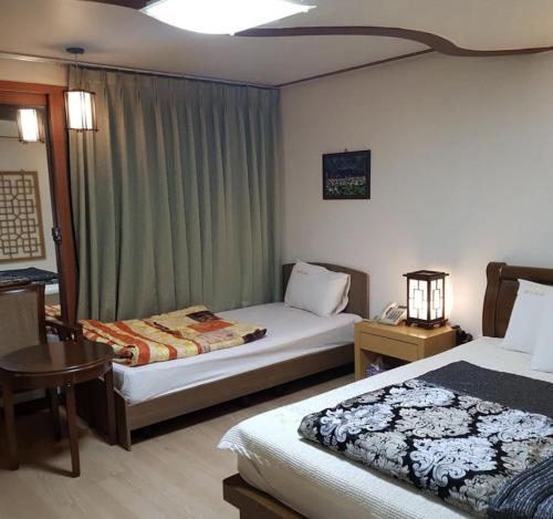ein Hotelzimmer mit zwei Betten und einem Tisch in der Unterkunft Jeonju Arirang in Jeonju