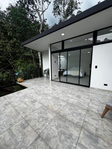 a house with glass doors and a patio at Sempiterno- la cabaña Whispering Wind in La Vega