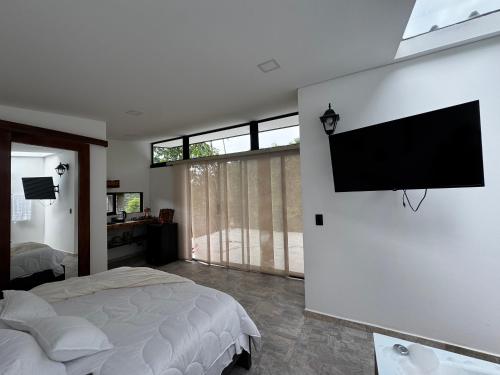 a bedroom with a bed and a flat screen tv on the wall at Sempiterno- la cabaña Whispering Wind in La Vega