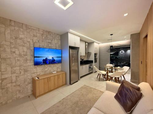 a living room with a couch and a tv on a wall at Studio Soberano - O mais luxuoso de CG in Campo Grande
