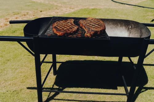 a grill with three pieces of meat on it at Tiny Huts Camp - Free Massage Hot Tub Sauna Waterfall Nearby in Tulbaghweg