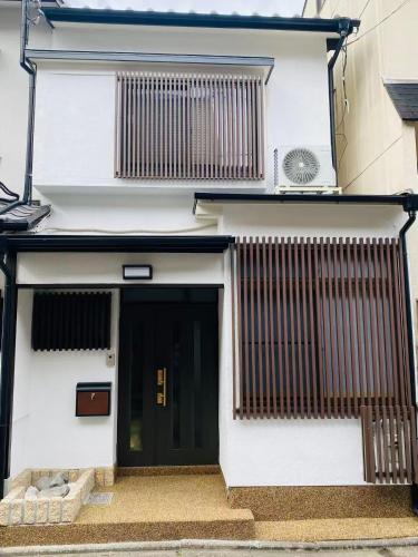 a white building with a black door and a fan at TAKEITEI Japanese-style lodge in Kyoto