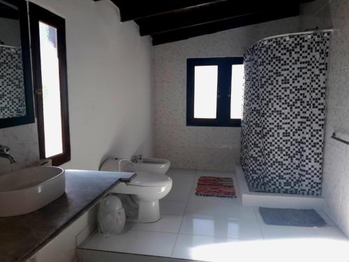 een badkamer met toilet, wastafel en douche bij Rincón de Nina in Tanti
