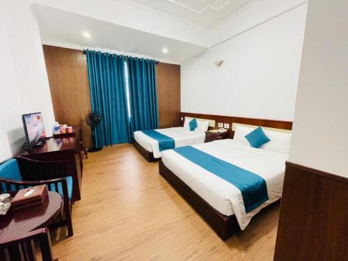 een hotelkamer met 2 bedden, een tafel en een bureau bij Khách Sạn Hùng Vương Quảng Ngãi in Quang Ngai