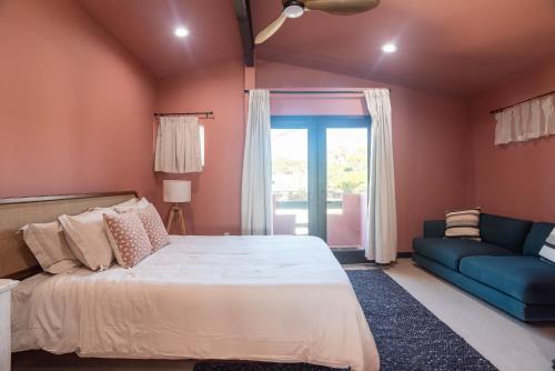a bedroom with a large bed and a blue couch at Rosarito Rosé in Las Gaviotas