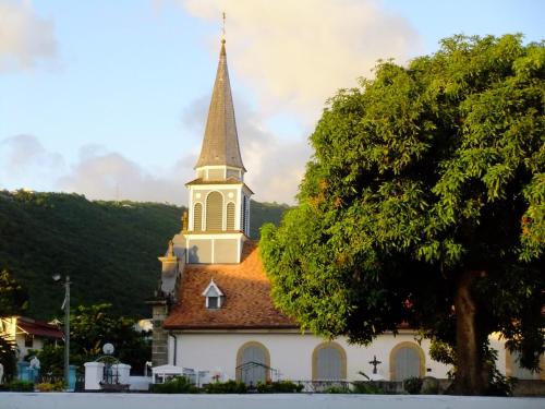 a church with a steeple with a tree in front at LOGEMENT REZ DE JARDIN A 4mn DES PLAGES in Case-Pilote