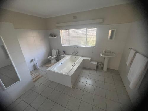 a bathroom with a tub and a toilet and a sink at Kremetart Villa in Alldays