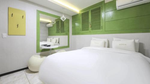 a bedroom with a white bed and green walls at Jeonju COJAJA in Jeonju
