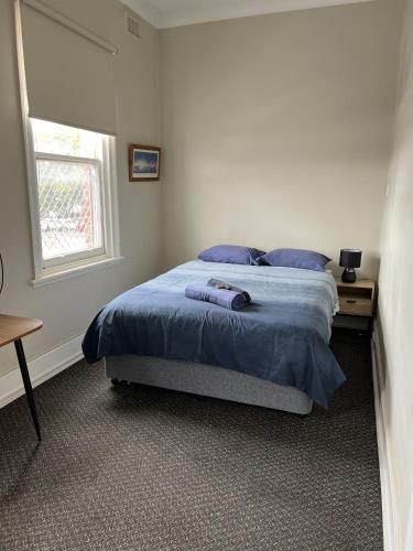 a bedroom with a bed with blue sheets and a window at Premier Hotel Collie in Collie