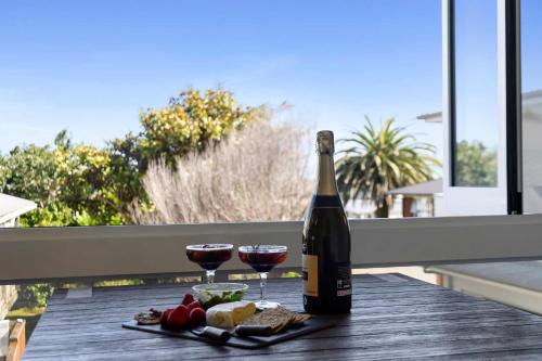 a bottle of wine and two glasses on a table at Beach Studio - coastal escape near Fitzroy Beach in New Plymouth
