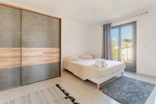 a bedroom with a bed and a large sliding glass door at L'Oasis de Saint-Quentin in Saint-Quentin-la-Poterie