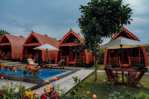 une rangée de chalets avec piscine, tables et chaises dans l'établissement Nusa Dua Huts Pondok Gajah Para by EPS, à Nusa Dua
