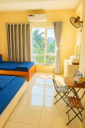 a bedroom with two beds and a desk and a window at Nhật Minh Motel Hải Phòng in Hai Phong