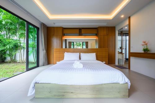 une chambre avec un grand lit et une grande fenêtre dans l'établissement New Luxury Pool Villa Bangtao Free Electricity & Daily Cleaning, à Ban Pak Lak