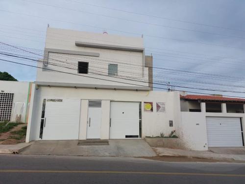 a white building with two doors and two garages at Pousada Luz do Sol in Piranhas