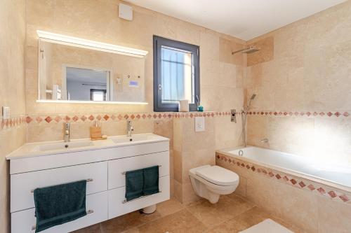 a bathroom with a toilet and a sink and a tub at L'Oasis de Saint-Quentin in Saint-Quentin-la-Poterie