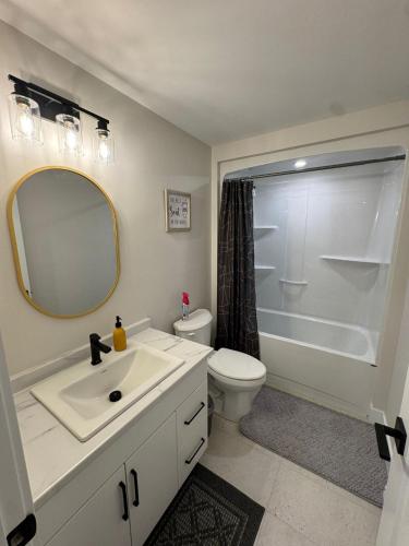 a bathroom with a sink and a toilet and a mirror at Cozy & Stylish Retreat with Modern Comforts in Moncton