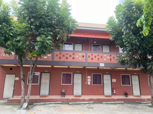 un edificio rosso con porte bianche e due alberi di Panngernpanthong inn resort a Ban Nong Chaeng