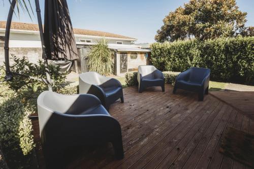 un groupe de chaises assises sur une terrasse en bois dans l'établissement Ropiha Retreat - close to Fitzroy Beach paradise, à New Plymouth