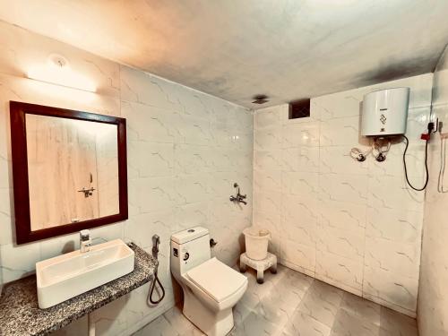 Un baño con un inodoro, un lavabo y un espejo. en Serendipity Desert Dunes Luxury Resort By Royal Empire, en Jaisalmer