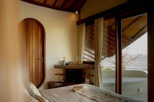 a bedroom with a bed and a window and a tub at Elysian Cove - One Bedroom Villa in Sekongkang Bawa