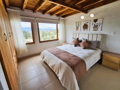 a bedroom with a large bed and a large window at Chalet Villa Serena in Villa de Leyva