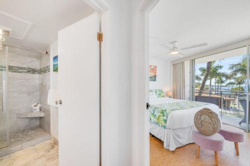 a bedroom with a bed and a walk in shower at Island Surf 306 · ISF 306 1BD w Ocean Views AC Pool Near Beach in Kihei