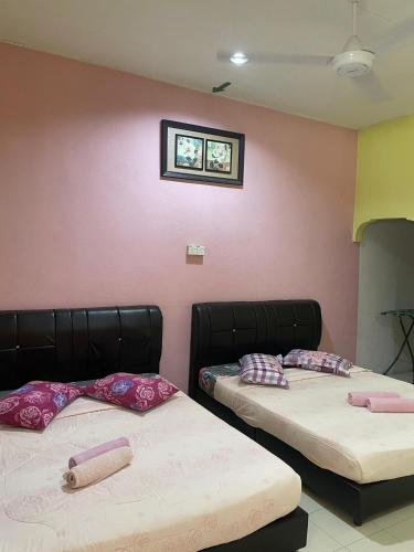 two beds with pillows on them in a room at Teratak Atok Ajib in Pantai Cenang