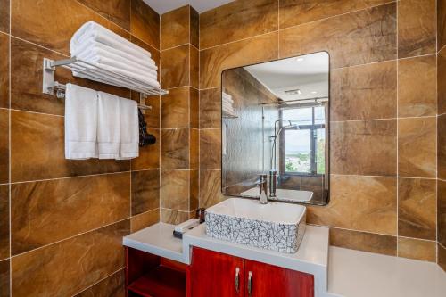 un baño con lavabo y espejo en Lijiang Tongfu Inn, en Lijiang