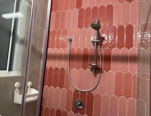a shower in a bathroom with a red wall at Mains Rd studio 带沙发阳光房 M8 in Brisbane