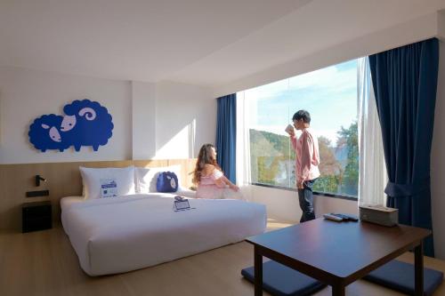 a boy and a girl looking out the window of a hotel room at Kokotel Rayong Beachfront in Ban Pak Khlong Phe