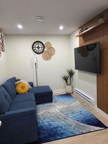 a living room with a blue couch and a tv at Cozy & Stylish 1BR Suite in Regina