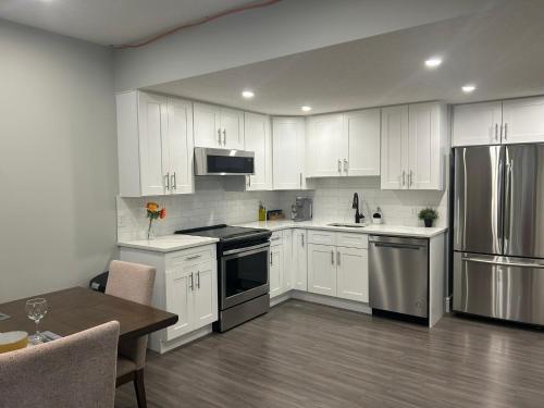 a kitchen with white cabinets and stainless steel appliances at Cozy Family Friendly Suite Near Whyte, UofA, Kinsmen with Desks or Home-office and Full Kitchen in Edmonton