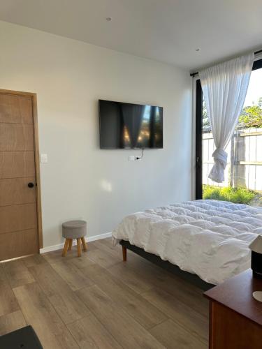 a bedroom with a bed and a tv on the wall at Loft Boutique Independiente Cochrane in Cochrane