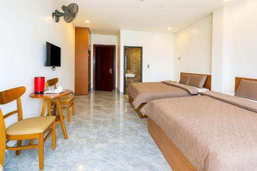 two beds in a hotel room with a table and chairs at Như Ý Hotel Hà Giang in Ha Giang