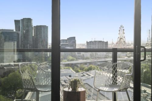 two chairs sitting on a balcony with a view of a city at Elegant 2-Bed with Superb Views & Amenities in Melbourne