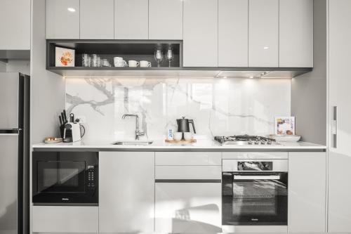 a white kitchen with a sink and a stove at Elegant 2-Bed with Superb Views & Amenities in Melbourne