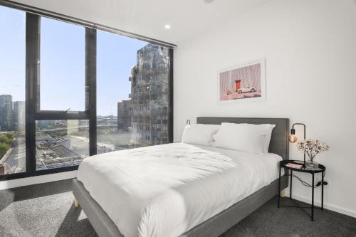 a bedroom with a large white bed and large windows at Elegant 2-Bed with Superb Views & Amenities in Melbourne