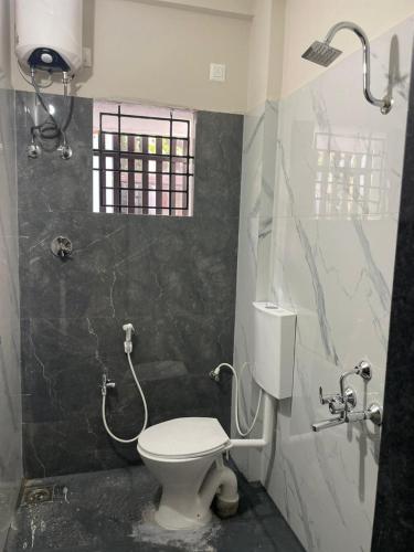 a bathroom with a toilet and a shower in it at Yashaswi Residency - F001 in Manipala