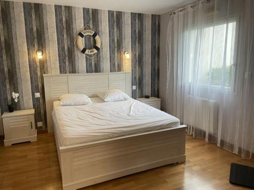 une chambre avec un lit blanc et une fenêtre dans l'établissement Appartement T3 rez-de-jardin, proche port Crouesty, wifi, parking - FR-1-775-39, à Arzon