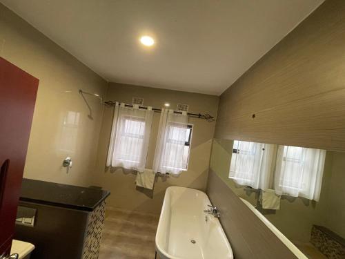 a bathroom with a tub and a toilet and windows at Better value stay in Lusaka