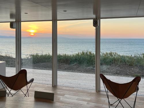 two chairs in a room with a view of the ocean at Cliff House MORAI 2 in Ishikari
