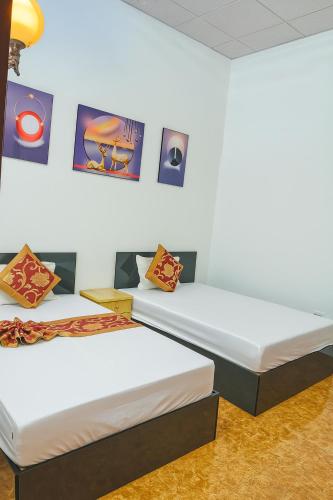 two beds in a room with posters on the wall at Hồng Trà Hotel Quảng Ninh in Quang Ninh