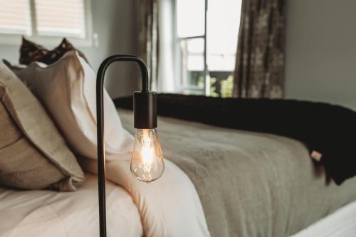 a light bulb sitting on a bed next to a bed at Buller Noire - luxury New Plymouth oceanview home in New Plymouth