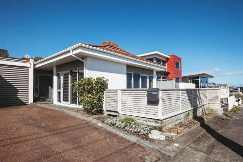 a white house with a red house at Holiday on Hamblyn - 2 BR home near Fitzroy Beach in New Plymouth