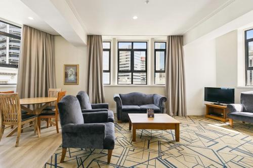 a living room with chairs and a table and a tv at Quest Wellington in Wellington
