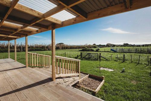 une terrasse en bois avec vue sur un champ dans l'établissement Weld Cottage - Sustainable lifestyle property, à New Plymouth