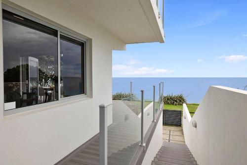 a white house with a view of the ocean at Beachfront Breeze - sea views for days in New Plymouth
